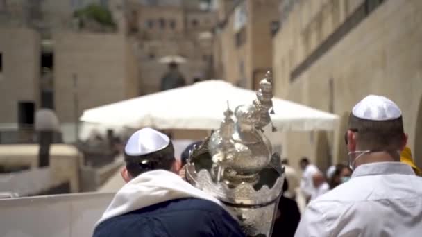 Homens não reconhecidos num evento do Bar Mitzvah. Jovem garoto judeu está tendo sua cerimônia pelo Muro das Lamentações andando e carregando o pergaminho da Torá liderado por seu pai e família filmados por trás, câmera lenta — Vídeo de Stock