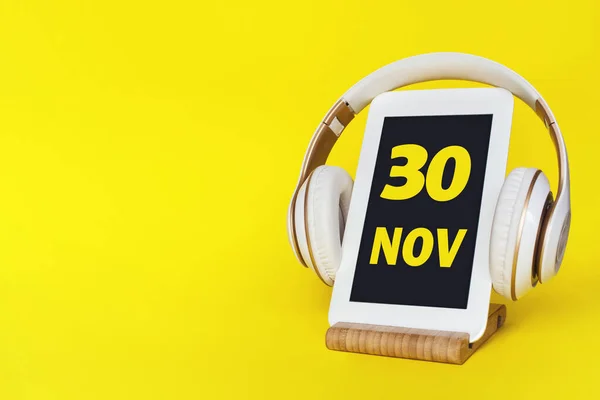 30 Kasım. Ayın 30 'u, takvim tarihi. Şık kulaklıklar ve sarı arka planda modern tablet. Mesaj için yer var. Eğitim, teknoloji, yaşam tarzı. Sonbahar ayı, yılın günü konsepti.