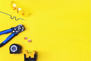 Sarı arka planda farklı elektrikçi malzemeleri var. Metin için alanı olan profesyonel elektrikçi araçlarının arkaplanı
