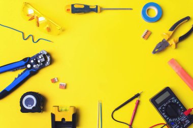 Sarı arka planda elektrikçi aletleri var. Elektrikçi araçları ve metin sarı arkaplan için alan ile düz konum