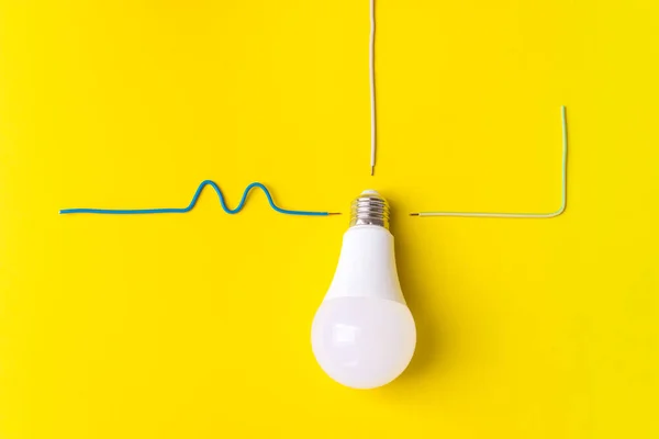 Led light bulb with connected wire phase, zero, ground on a yellow background. New technology of energy, Eco power concept. Copy space. Power saving concept
