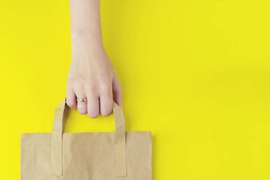 Kahverengi, boş, boş bir kağıt torba, sarı arka planda paket servisi için. Paketleme şablonu modeli. Teslimat hizmeti konsepti. Alan Reklam Alanını Kopyala