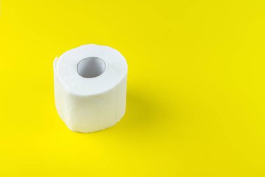 Reklam için sarı arka planda tuvalet kağıdı rulosu.