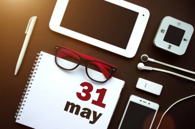 31 Mayıs. Ayın 31 'i, takvim tarihi. Laptop, defter, ofis malzemeleri ve kahverengi sırtında kırtasiye malzemesi olan ofis işyeri. Bahar ayı, yılın günü konsepti.