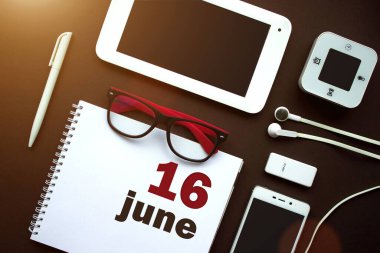 16 Haziran. Ayın 16 'sı, takvim tarihi. Laptop, defter, ofis malzemeleri ve kahverengi sırtında kırtasiye malzemesi olan ofis işyeri. Yaz ayı, yılın günü konsepti.