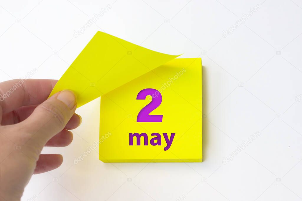 May 2nd. Day 2 of month, Calendar date. Hand rips off the yellow sheet of the calendar. Spring month, day of the year concept