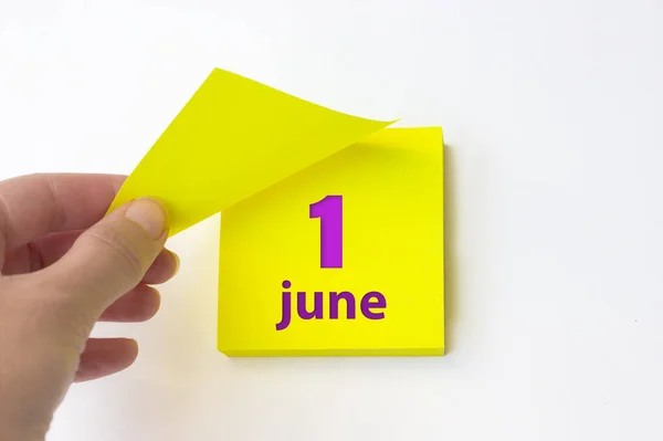 June 1st . Day 1 of month, Calendar date. Hand rips off the yellow sheet of the calendar. Summer month, day of the year concept