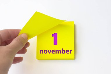 November 1st . Day 1 of month, Calendar date. Hand rips off the yellow sheet of the calendar. Autumn month, day of the year concept