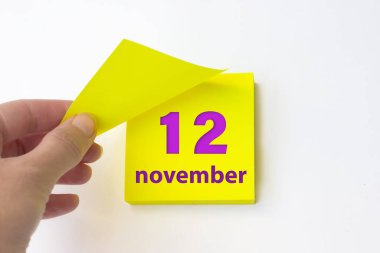November 12nd. Day 12 of month, Calendar date. Hand rips off the yellow sheet of the calendar. Autumn month, day of the year concept