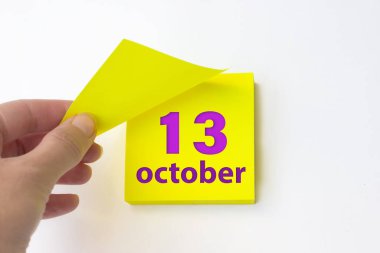 October 13rd. Day 13 of month, Calendar date. Hand rips off the yellow sheet of the calendar. Autumn month, day of the year concept