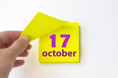 October 17th. Day 17 of month, Calendar date. Hand rips off the yellow sheet of the calendar. Autumn month, day of the year concept