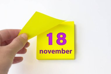 November 18th. Day 18 of month, Calendar date. Hand rips off the yellow sheet of the calendar. Autumn month, day of the year concept