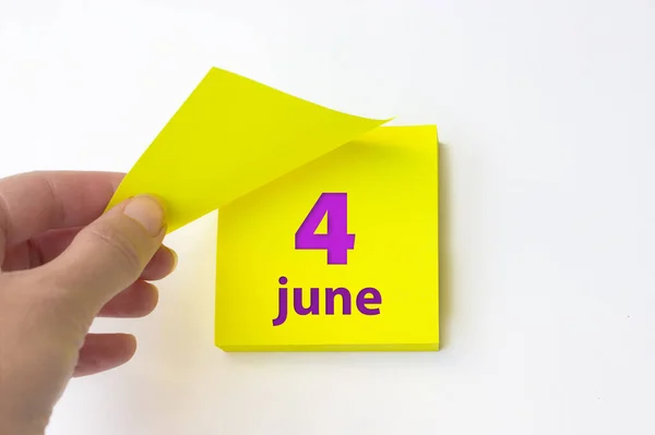 June 4th. Day 4 of month, Calendar date. Hand rips off the yellow sheet of the calendar. Summer month, day of the year concept
