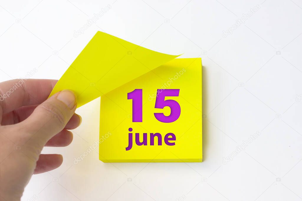 June 15th. Day 15 of month, Calendar date. Hand rips off the yellow sheet of the calendar. Summer month, day of the year concept