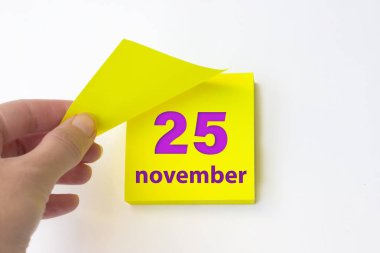 November 25th. Day 25 of month, Calendar date. Hand rips off the yellow sheet of the calendar. Autumn month, day of the year concept