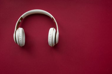 Kırmızı arka planda beyaz kablosuz kulaklık. Üst görünüm.