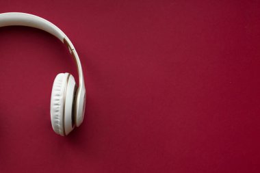 Kırmızı arkaplanı olan beyaz kulaklıklı. Müzik sesi için kulaklıklar
