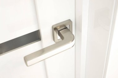 Krom kapı kolu olan modern beyaz bir kapı. Mobilya konsepti