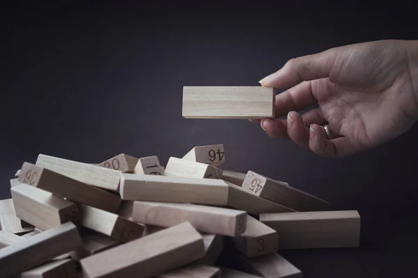 Hand pulls out a wooden Block from a pile of the same blocks. Human resources, management, recruitment