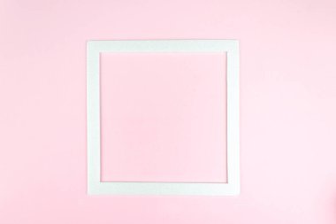 Pembe, minimalist kavram üzerine beyaz kare çerçevenin üst görüntüsü. Kare boş kart modellemesi