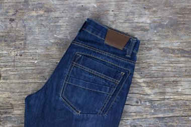 Ahşap arka planda pantolonlar, düz yatış. Modaya uygun kıyafetler.