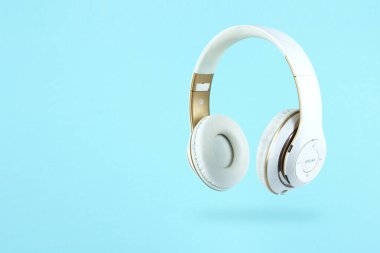 Mavi arka planda beyaz kablosuz kulaklık. Müzik konsepti