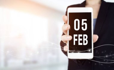 February 5th. Day 5 of month, Calendar date. White smartphone with Calendar date in businesswoman hand on blurred background. Winter month, day of the year concept clipart