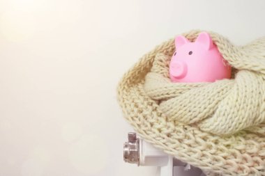 Isıtma radyatörü, domuz kumbarası ve örgü atkısı. Evde ısıtma için ödeme yapma kavramı.