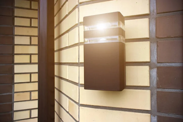 家の壁に太陽の光で外に置かれたスタイリッシュなランタン 照明用の近代的な電気機器 — ストック写真