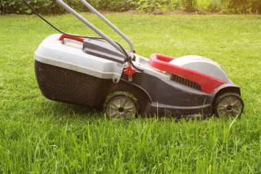 Lawn mower on a green meadow. Lawn Mower In Garden. Details of landscaping and gardening