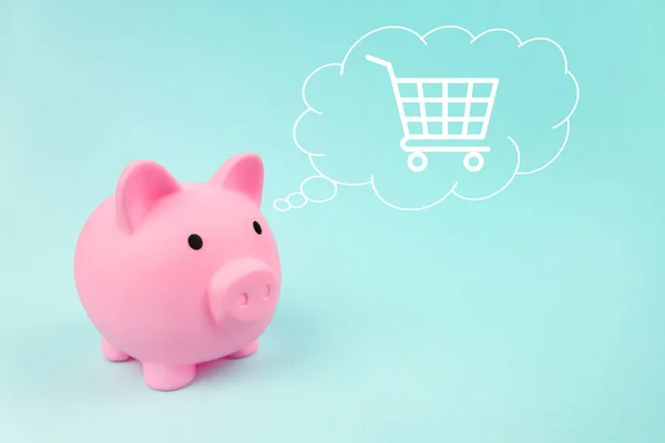 Pink piggy bank with trolley digital hologram in cloud thought above his head on blue background