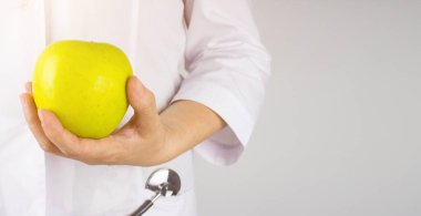 Beslenme uzmanı Doktor El Kalçada Yeşil Elma Gösteriyor. Taze yeşil bir elmayı tutan beslenme uzmanı doktorun eli. Sağlıklı beslenme