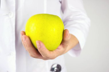 Doctor holds green apple. Big green apple in doctor's hand. Health in your hands.