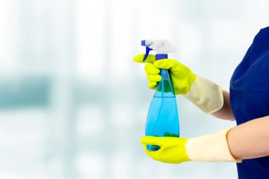 Bulanık arka planda deterjanı olan temizlikçi kadın. Temizlik ve dezenfeksiyon kavramı.