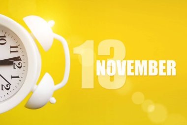 13 Kasım. Ayın 13 'ü, takvim tarihi. Takvim günüyle birlikte sarı arka planda beyaz çalar saat. Sonbahar ayı, yılın günü konsepti.