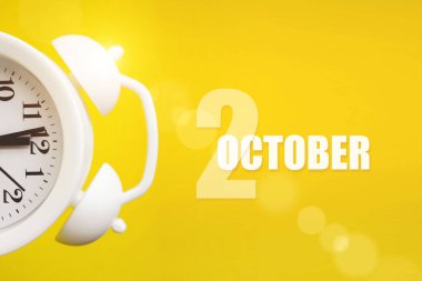 2 Ekim. Ayın ikinci günü, takvim tarihi. Takvim günüyle birlikte sarı arka planda beyaz çalar saat. Sonbahar ayı, yılın günü konsepti.
