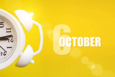 6 Ekim. Ayın 6 'sı, takvim tarihi. Takvim günüyle birlikte sarı arka planda beyaz çalar saat. Sonbahar ayı, yılın günü konsepti.