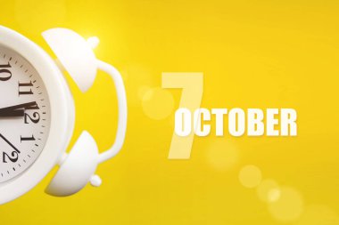 7 Ekim. Ayın yedinci günü, takvim tarihi. Takvim günüyle birlikte sarı arka planda beyaz çalar saat. Sonbahar ayı, yılın günü konsepti.