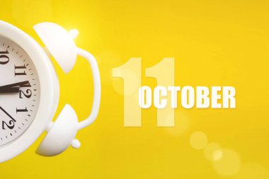 11 Ekim. Ayın 11 'i, takvim tarihi. Takvim günüyle birlikte sarı arka planda beyaz çalar saat. Sonbahar ayı, yılın günü konsepti.