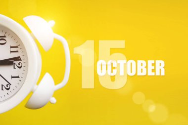 15 Ekim. Ayın 15 'i, takvim tarihi. Takvim günüyle birlikte sarı arka planda beyaz çalar saat. Sonbahar ayı, yılın günü konsepti.