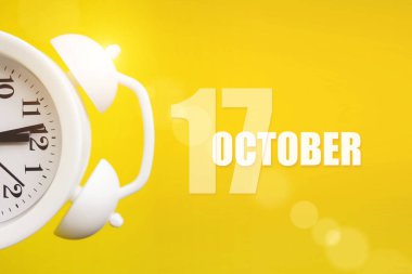 17 Ekim. Ayın 17 'si, takvim tarihi. Takvim günüyle birlikte sarı arka planda beyaz çalar saat. Sonbahar ayı, yılın günü konsepti.