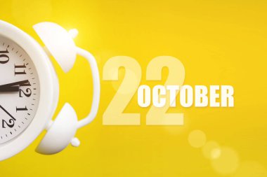 22 Ekim. Ayın 22 'si, takvim tarihi. Takvim günüyle birlikte sarı arka planda beyaz çalar saat. Sonbahar ayı, yılın günü konsepti.