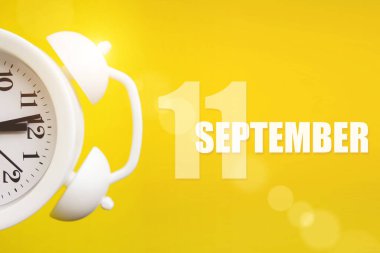 11 Eylül. Ayın 11 'i, takvim tarihi. Takvim günüyle birlikte sarı arka planda beyaz çalar saat. Sonbahar ayı, yılın günü konsepti.