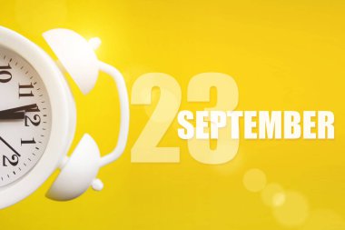 23 Eylül. Ayın 23 'ü, takvim tarihi. Takvim günüyle birlikte sarı arka planda beyaz çalar saat. Sonbahar ayı, yılın günü konsepti.