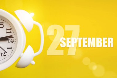27 Eylül. Ayın 27 'si, takvim tarihi. Takvim günüyle birlikte sarı arka planda beyaz çalar saat. Sonbahar ayı, yılın günü konsepti.