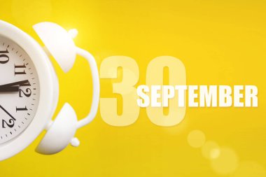 30 Eylül. Ayın 30 'u, takvim tarihi. Takvim günüyle birlikte sarı arka planda beyaz çalar saat. Sonbahar ayı, yılın günü konsepti.