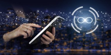 Sınırsız internet kavramı. Şehrin karanlık arka planında dijital hologram sonsuzluk işareti olan beyaz tablete dokun. Fikir, yaşam, başarı, iş