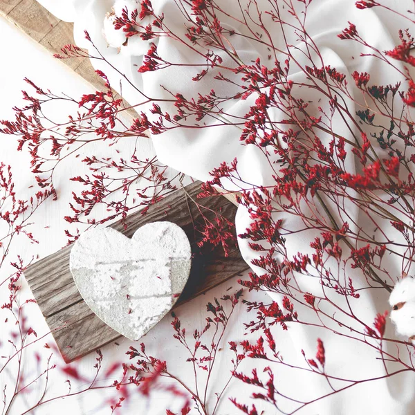 Λευκή Ζωγραφισμένη Ξύλινη Καρδιά Δίπλα Κόκκινα Αποξηραμένα Λουλούδια Και Λευκό — Φωτογραφία Αρχείου