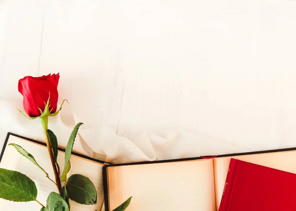 Red rose next to open books and closed books on white background. Perfect for Sant Jordi or for Valentine\'s Day.