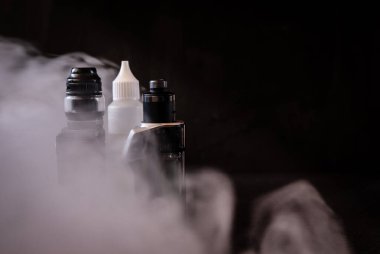 Vapers and liquid to vape between vapor on black background.